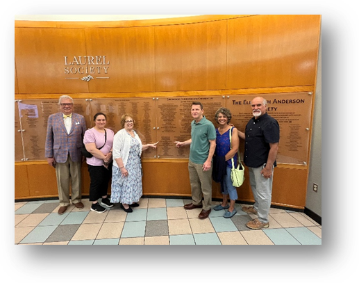 A group of people standing in front of a plaqueAI-generated content may be incorrect.