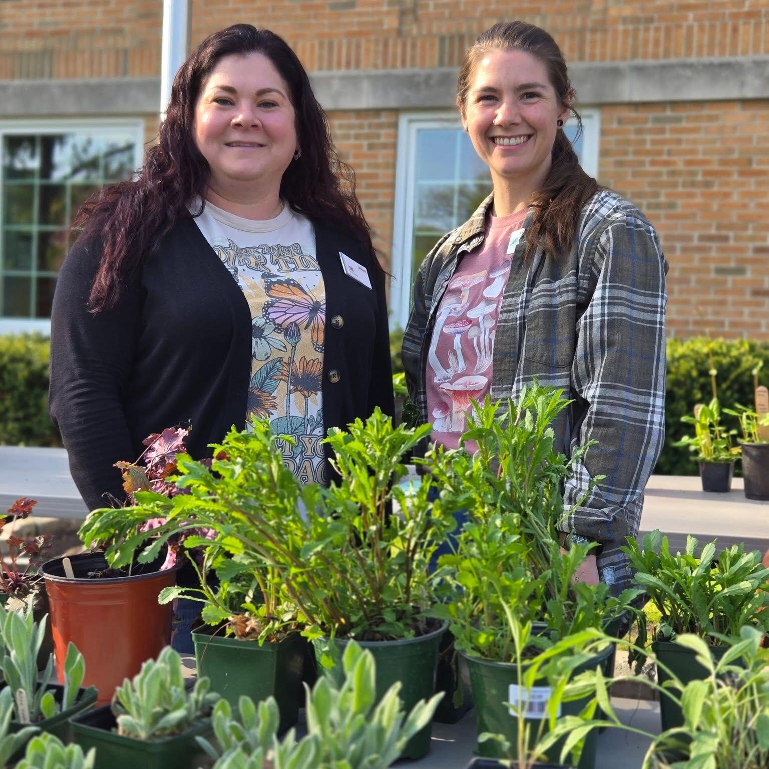 Two friendly library staff stand behind plant at the native plant exchange at Cromaine Library